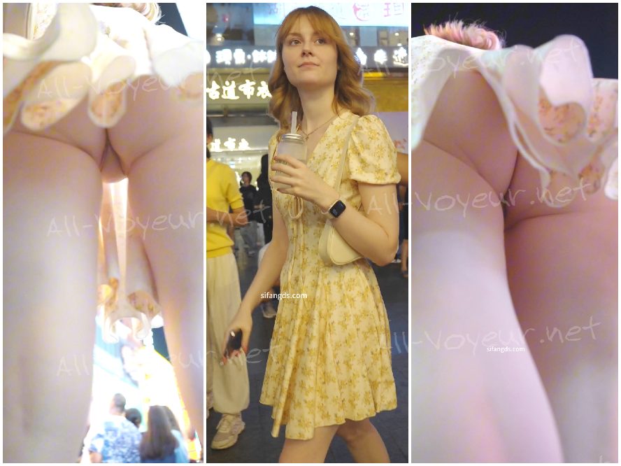 花柄のスカートをはいた美しい女性が、エスカレーターに足をかがめて下着を露わにしながら立っています。列に並んでいる間、ローアングルで撮影されています。