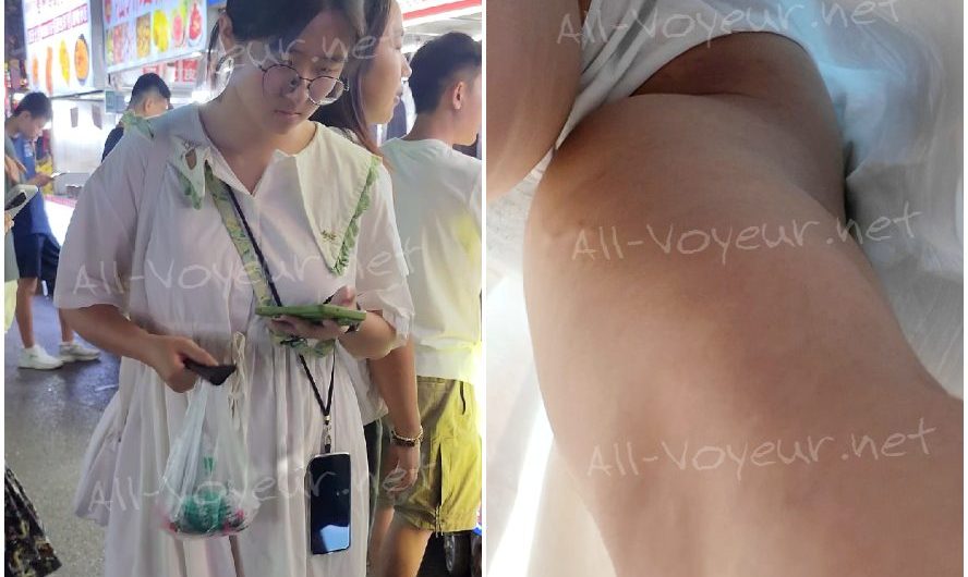 白いマキシドレスを着て、ハンドバッグを持ち、眼鏡をかけた女子大生をこっそり撮影する。